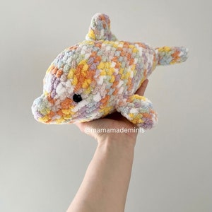 May include: A crocheted dolphin plush toy in a rainbow color pattern. The dolphin is made with a soft, fluffy yarn and has a sweet, friendly expression.
