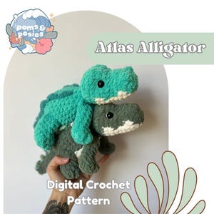 Op de afbeelding: Twee gehaakte alligatorspeelgoed, één turquoise en één grijs, op elkaar gestapeld. De bovenste alligator is turquoise met een witte buik en de onderste alligator is grijs met een witte buik. De tekst "Atlas Alligator" en "Digital Crochet Pattern" zijn ook zichtbaar.