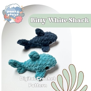 May include: Two crocheted shark toys, one dark blue and one turquoise, are displayed. The text "Bitty White Shark" is above the sharks, and "Digital Crochet Pattern" is below. The sharks have white bellies and black eyes.