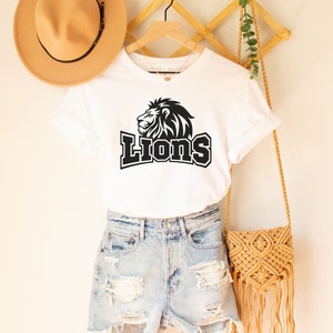 May include: White t-shirt with a black lion graphic and the word "LIONS" in black text.