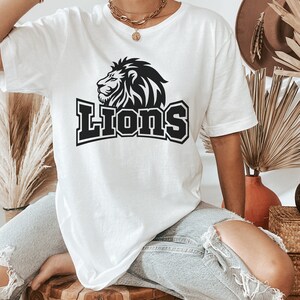 May include: White oversized t-shirt with a black lion graphic and the word "Lions" in bold black letters.