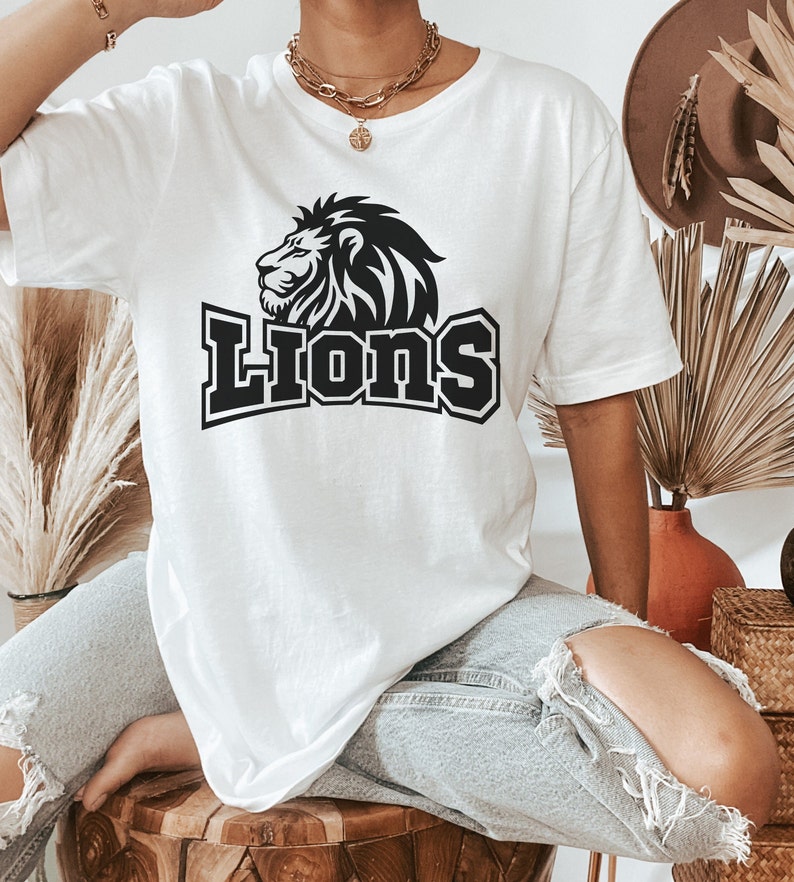 May include: White oversized t-shirt with a black lion graphic and the word "Lions" in bold black letters.