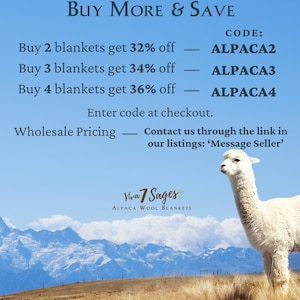 a white llama standing in a field with mountains in the background