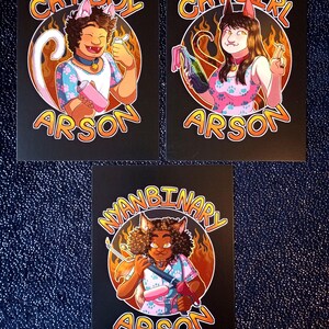 Może przedstawiać: Trzy czarne grafiki przedstawiające postacie z kreskówek z kocimi uszami i słowem "Arson". Grafiki zawierają "Cat Boy", "Cat Girl" i "Nyanbinary" z płomieniami i okrągłym wzorem.