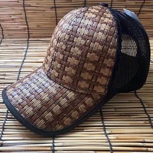 Może przedstawiać: Czapka bejsbolowa z brązowego i beżowego splotu z tyłu z siatką w kolorze czarnym. Czapka ma zakrzywiony daszek i czarny regulowany pasek.