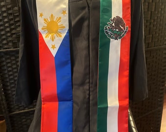 May include: A black graduation gown with a red, white, and blue sash featuring the flag of the Philippines and a green, white, and red sash featuring the flag of Mexico.