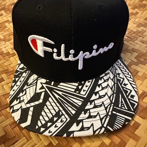 Peut inclure: Casquette de baseball à motif noir et blanc avec une couronne noire et une visière blanche. La couronne est ornée d'un logo brodé blanc qui dit "Filipino" avec un logo "C" rouge et blanc au-dessus du mot.