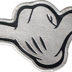 May include: Embroidered patch featuring a stylized, light gray hand with black outlines and details. The patch has a black border and a stitched, light gray edge. The hand is in a relaxed, open position, with visible finger lines.
