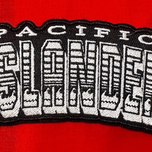 May include: Black and white embroidered patch with the text "PACIFIC ISLANDER" in a stylised font.