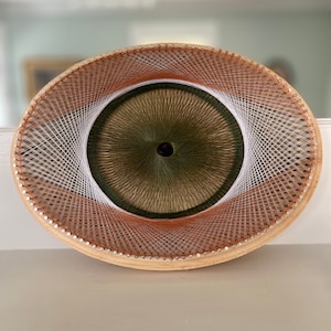 May include: A circular string art piece with a wooden frame and a green, white, and brown string design.