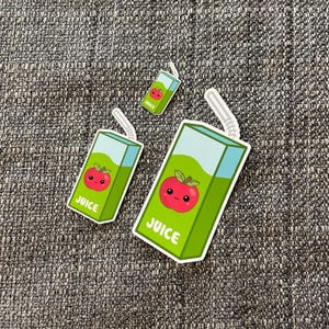 May include: Three green and white juice box stickers with a red apple and the word "JUICE" on each. The apple has a smiling face.