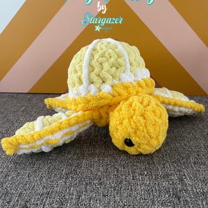May include: A crocheted turtle toy in yellow and white, resembling a lemon. The turtle has a round head, a shell, and flipper-like appendages. The text "Citrus Turtles" and "Crochet Pattern" are visible.