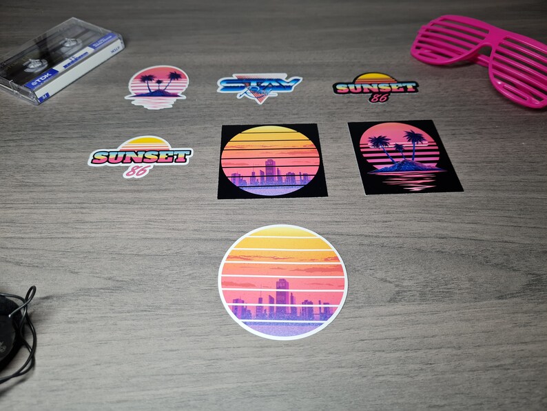 Pu&ograve; includere: Un set di otto adesivi in stile retr&ograve; con un tramonto, palme e il testo "Sunset 86" e "Stay". Gli adesivi sono stampati su carta bianca con una finitura lucida.