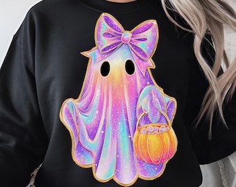 Puede incluir: Sudadera negra con un diseño de fantasma colorido. El fantasma tiene un gran lazo morado, un contorno dorado y sostiene una cesta con forma de calabaza. El cuerpo del fantasma es una mezcla de tonos rosa, morado y azul.