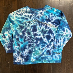 May include: A blue and white tie-dye sweatshirt with long sleeves and a crew neck.
