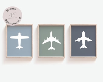 May include: Three framed prints of white airplane silhouettes on different colored backgrounds. The prints are in light blue, sage green, and dark blue frames.
