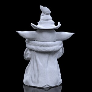 K&ouml;nnte beinhalten: Eine wei&szlig;e 3D-gedruckte Figur eines Charakters, der einen spitzen Hut tr&auml;gt. Der Charakter sitzt mit gekreuzten Armen und ist von der Kamera abgewandt.