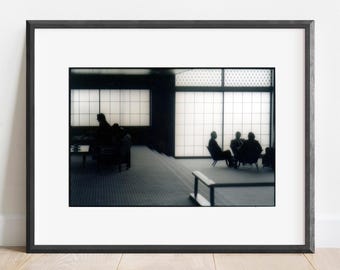 May include: A framed photograph depicting a dark interior space with silhouettes of people seated in chairs. The background features large, grid-patterned translucent windows that emit bright light, creating a high-contrast scene.
