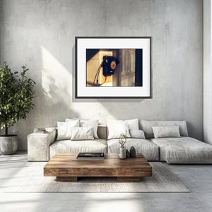 May include: A framed wall art print featuring a black vintage wall-mounted telephone with a circular dial and a hanging handset, displayed in a room with a light gray sofa, a wooden coffee table, and a potted plant.