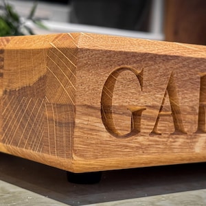 Puede incluir: Una tabla de cortar de madera con un acabado natural y la palabra "GARDEN" tallada en la superficie.