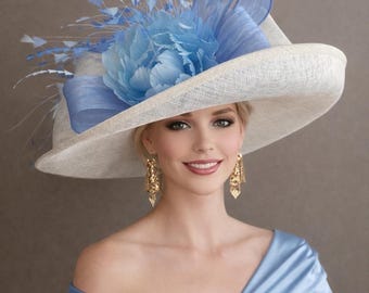 May include: A wide-brimmed cream-colored hat featuring a large light blue fabric flower, matching blue ribbon loops, and delicate blue feathers. The hat is paired with gold dangling earrings and a light blue satin off-the-shoulder garment.