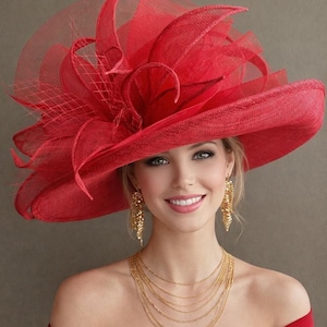 May include: A vibrant red hat with a wide brim and decorative accents. The hat features a layered design with a mesh veil and is paired with gold jewelry. The overall look is elegant and suitable for special occasions.