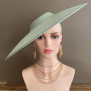 May include: A mint green hat with a wide brim, displayed on a mannequin head. The hat is paired with gold-colored layered necklaces and dangling earrings. The mannequin has a fair complexion and is set against a neutral background.
