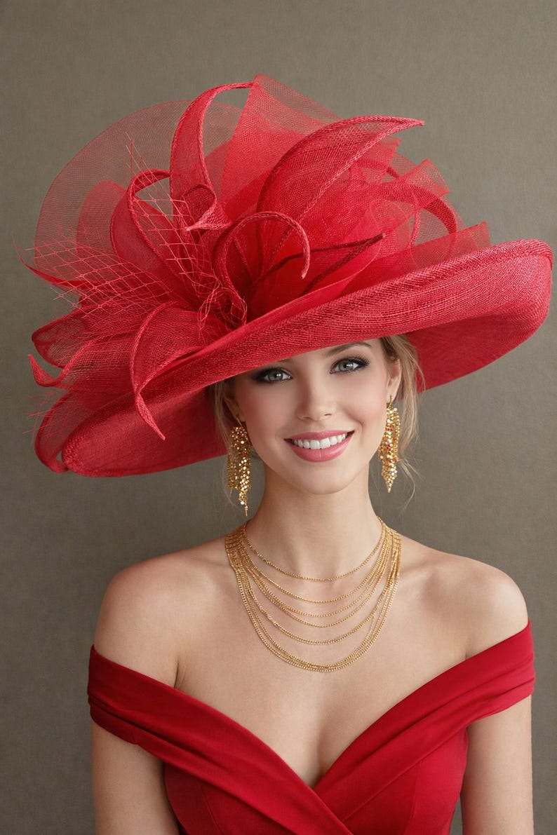 May include: A woman wearing a vibrant red hat with a wide brim and elaborate floral and netting accents. She is also wearing gold earrings and a layered gold necklace, and a red off-the-shoulder dress.