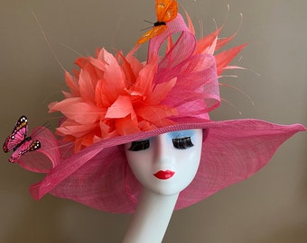 Sombrero Kentucky Derby de ala ancha de color rosa brillante con lazo de Sinamay y flores y mariposas de plumas de color rosa coral/naranja. Sombrero de té del día de la madre