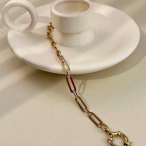 May include: A gold chain bracelet with a simple, rectangular link design. The bracelet has a secure clasp.