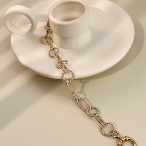 May include: A gold chain bracelet with a mix of oval and twisted links. The bracelet has a lobster clasp closure.