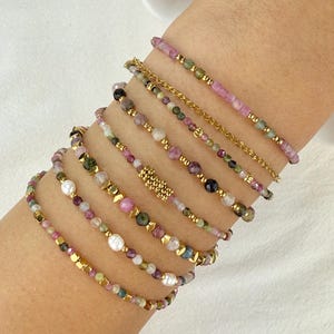 Roestvrijstalen armband met natuurlijke toermalijn edelstenen in diverse kleuren en gouden bedeltjes.