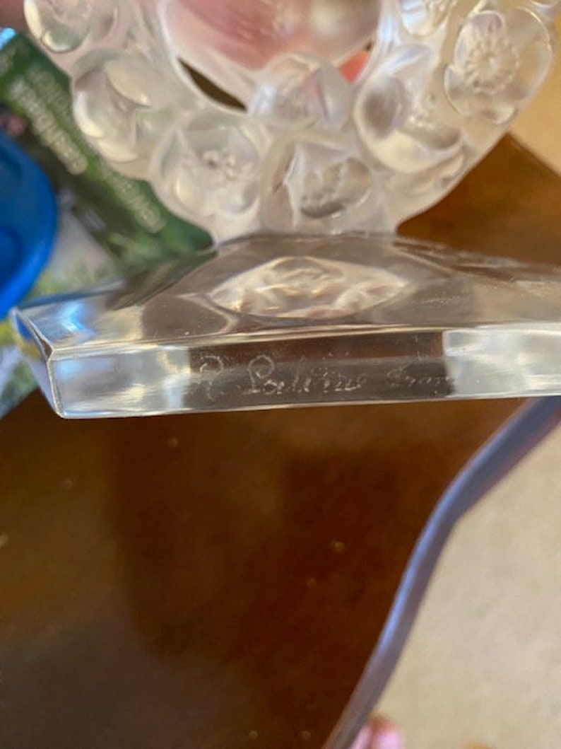 K&ouml;nnte beinhalten: Eine klare Glasskulptur mit floralem Design. Die Basis der Skulptur ist ein klares Glasoktagon mit der Inschrift "Baccarat France" auf der Unterseite.