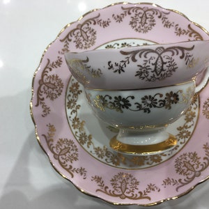May include: A pink and white teacup and saucer set with gold trim and floral designs.