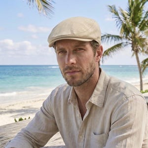Peut inclure: Casquette de style gavroche beige clair. Le chapeau est fait d'un tissu de couleur claire et a une couronne arrondie et un petit bord rigide. La personne porte une chemise boutonnée beige clair. En arrière-plan, une plage avec des palmiers et l'océan.