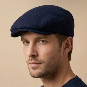 Op de afbeelding: Een marineblauwe pet met een afgeronde kroon en een kleine klep. De pet is gemaakt van een zachte, getextureerde stof. Een klassieke stijl tegen een effen, neutrale achtergrond.