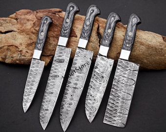 May include: A collection of six Damascus steel kitchen knives. Each knife features a distinctive water-like pattern on the blade and a dark grey wooden handle with silver bolsters and brass rivets. The knives are displayed on a piece of wood.