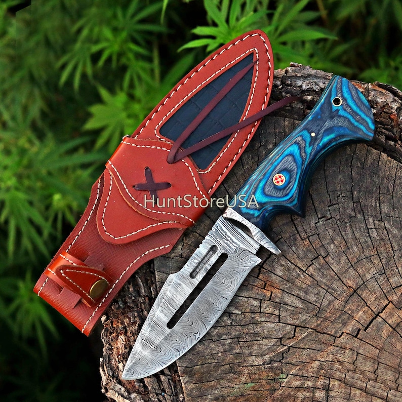 May include: A blue and black patterned knife with a Damascus steel blade and a leather sheath. The knife has a red cross on the handle.