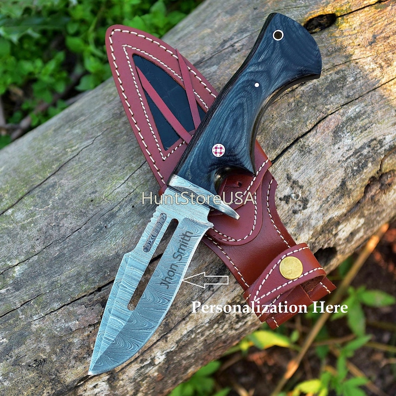 May include: A black and silver hunting knife with a wooden handle and a leather sheath. The knife has a personalized inscription that reads "John Smith".