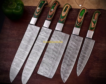 Puede incluir: Un juego de cinco cuchillos de cocina de acero de Damasco con mangos de madera. Los mangos son una combinación de madera verde y marrón, con virolas plateadas. Las hojas tienen un diseño único. Un pimiento verde es visible en el fondo.