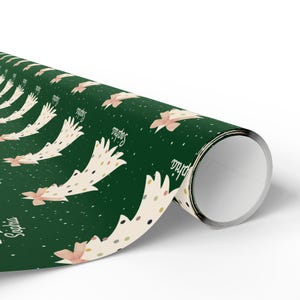 May include: Green wrapping paper with a repeating pattern of white Christmas trees with pink bows and gold polka dots. The trees have the name "Sophia" written on them.