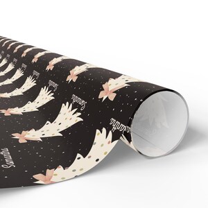 May include: Black wrapping paper with a repeating pattern of white Christmas trees with gold and pink polka dots and a pink bow. The text "Samantha" is repeated throughout the pattern.