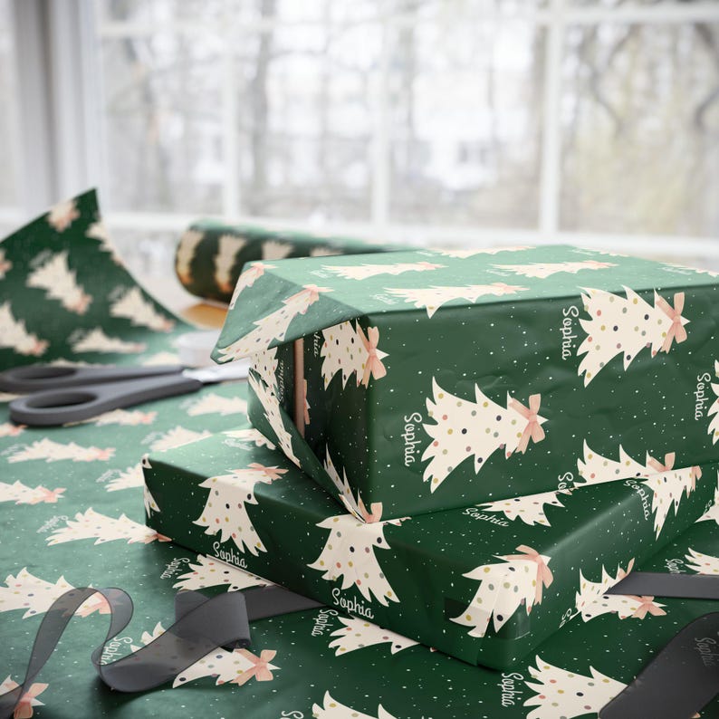 May include: Green wrapping paper with a white and pink Christmas tree pattern. The paper has the name "Sophia" repeated throughout the design.
