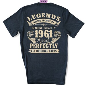 Op de afbeelding: Een donkerblauw T-shirt met een vintage-stijl grafische afbeelding met de tekst "Legends were born in 1961. Genuine Quality. One of a Kind. Limited Edition. Aged Perfectly. All Original Parts."