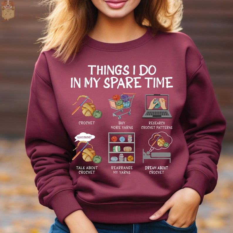 May include: A maroon sweatshirt with the text "Things I do in my spare time" and illustrations of crocheting, buying yarn, researching crochet patterns, talking about crochet, rearranging yarn, and dreaming about crochet.