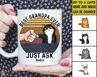 May include: White ceramic coffee mug with a retro design featuring a cat and the text "Best Grandpa Ever" and "Just Ask Audra".