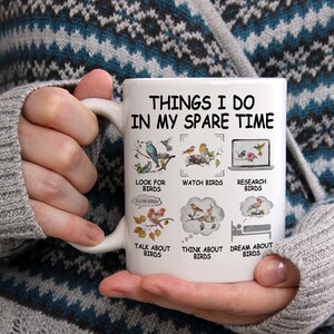May include: White ceramic coffee mug with a black design that says "Things I do in my spare time" and lists activities related to birds. The activities include looking for birds, watching birds, researching birds, talking about birds, thinking about birds, and dreaming about birds.