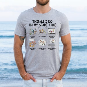 May include: A gray t-shirt with the text "Things I do in my spare time" and a list of activities related to birds. The activities include looking for birds, watching birds, researching birds, talking about birds, thinking about birds, and dreaming about birds.
