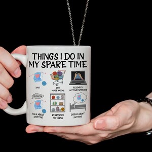 May include: White ceramic mug with a black outline and the text "Things I do in my spare time". The mug has illustrations of knitting needles, yarn, a shopping cart, a laptop, and a bed.