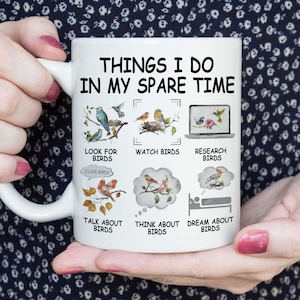 May include: White ceramic mug with a humorous design featuring a list of things the owner does in their spare time, all related to birds. The text reads "Things I do in my spare time" and includes illustrations of birds and phrases like "Look for birds", "Watch birds", "Research birds", "Talk about birds", "Think about birds", and "Dream about birds".